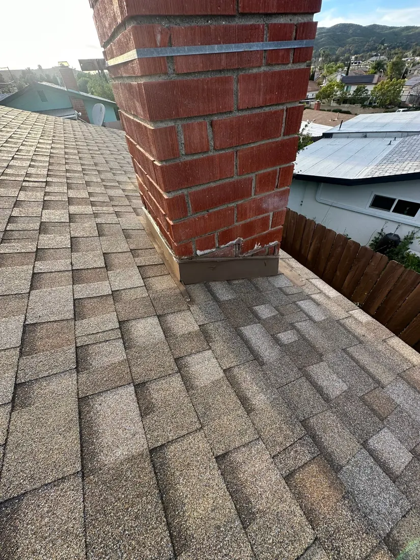 Completed painted chimney flashing on an architectural shingle roof