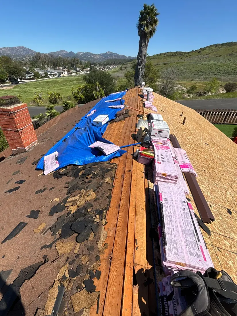 Asphalt shingle tear-off revealing plank decking and new plywood installation