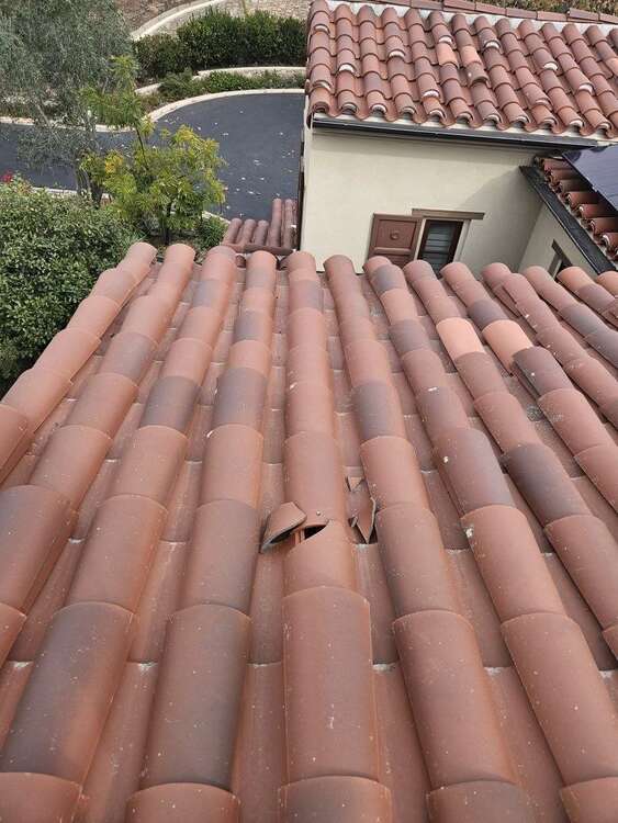 Multiple broken concrete barrel roof tiles in an exposed roof field
