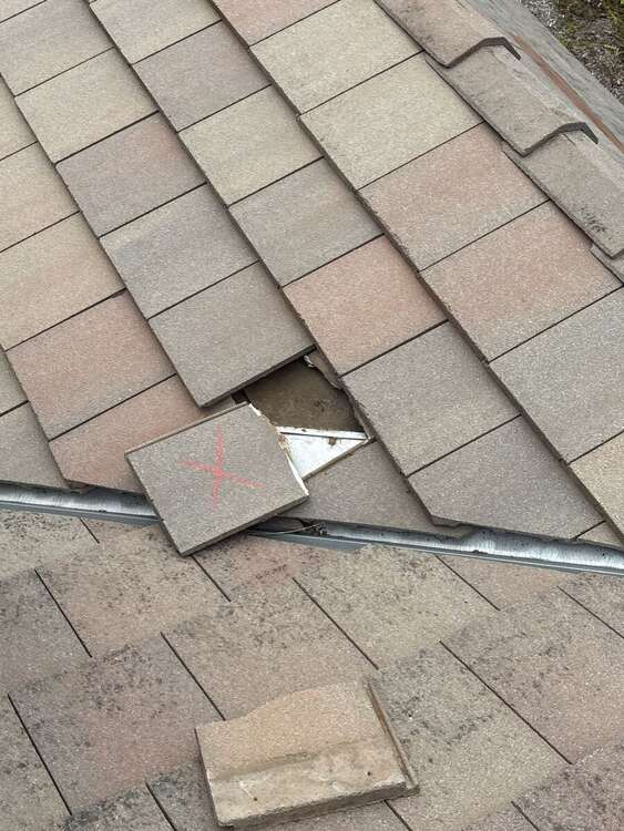 Broken concrete flat tile at roof edge with flashing visible below