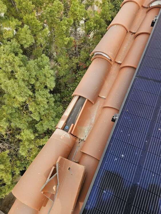 Concrete roof tiles lifted near an opening, revealing the roof area below