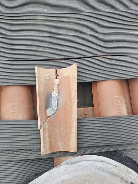 Broken roof tile near solar panels with adhesive visible across the damaged tile