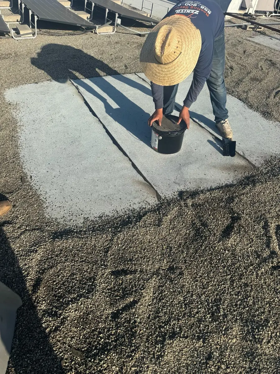 Zenith roofer applying built-up roof repair materials around a repaired area