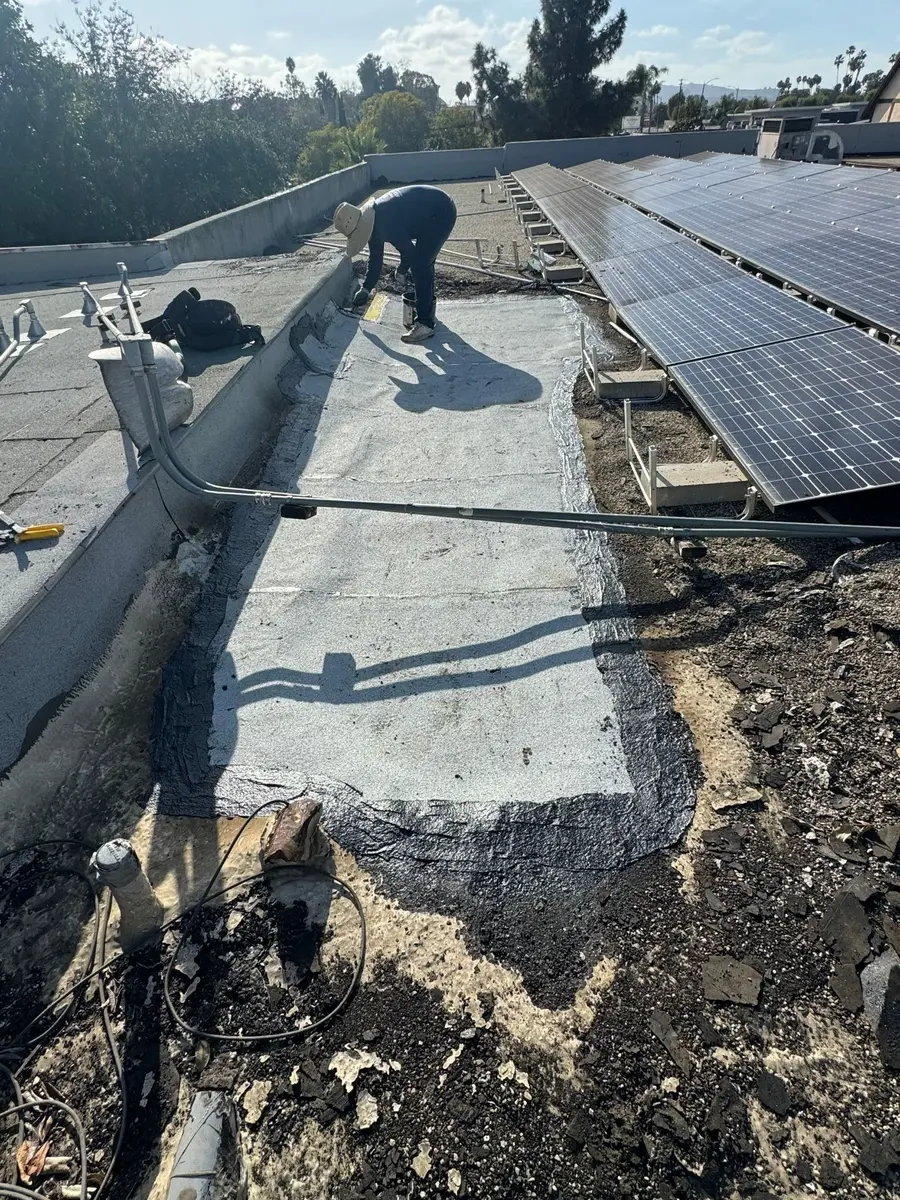 Long flat roof repair area beside solar panels, conduits and rooftop equipment