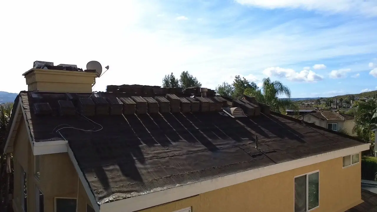 Aged black tile roof underlayment exposed after the concrete tiles were lifted