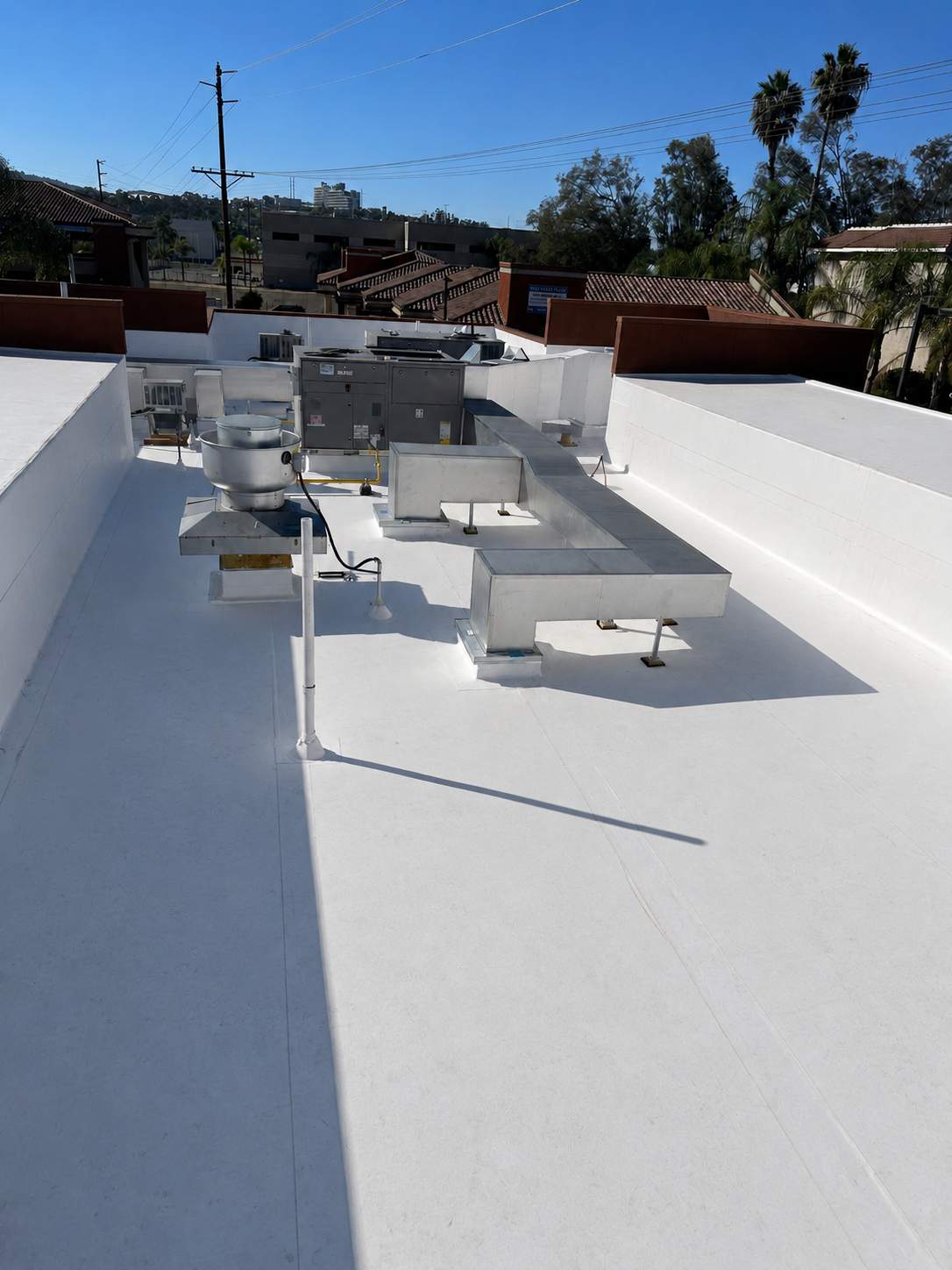 Completed white low-slope roof restoration around rooftop equipment