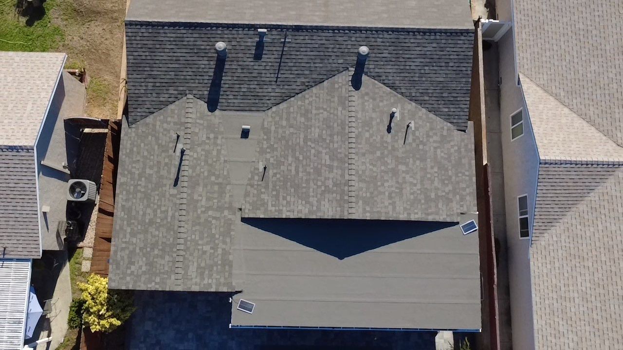 Aerial view of a completed low-slope roof and surrounding shingle roof