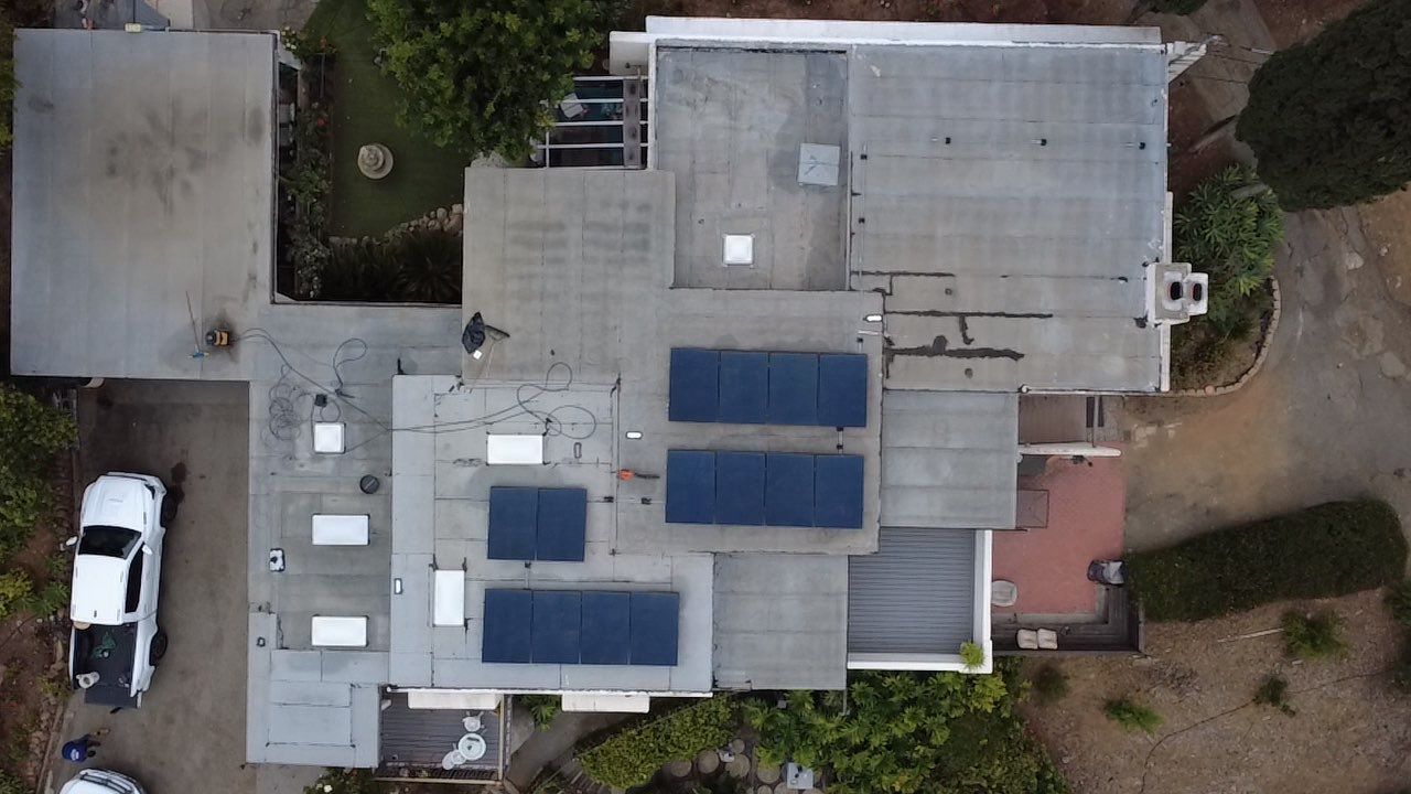 Aerial view of a low-slope roof with solar panels before silicone restoration