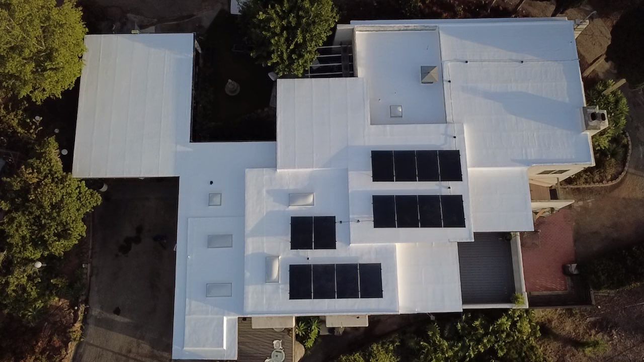 Aerial view of completed white silicone-coated roofs with solar panels