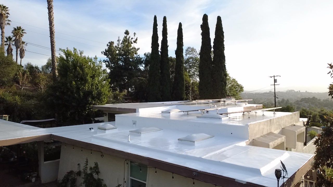 Completed white silicone roof restoration across several low-slope roof areas