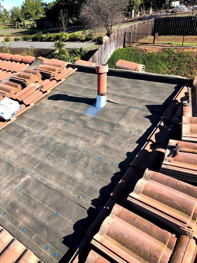 Tile roof repair in progress—broken tiles replaced and sealed