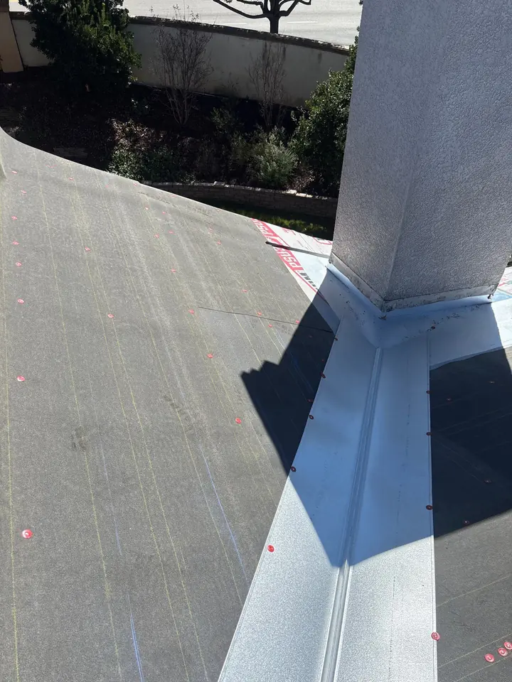 Detailed underlayment and metal flashing around a tile roof chimney