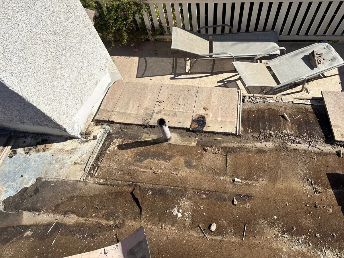 Tile removed around a chimney exposing aged and torn roof underlayment