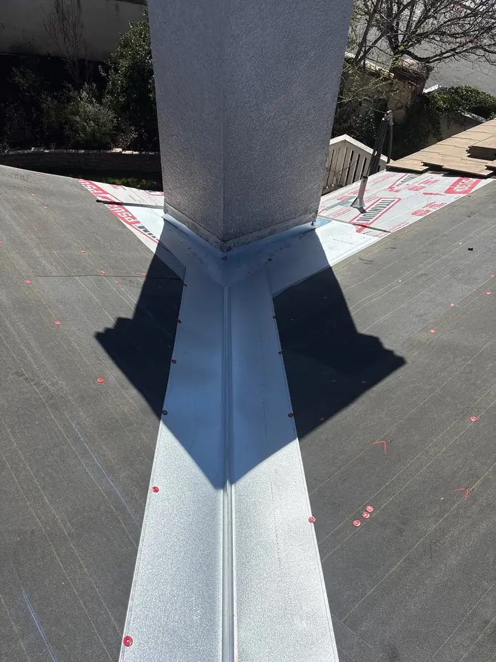 New chimney saddle and valley metal integrated with tile roof underlayment