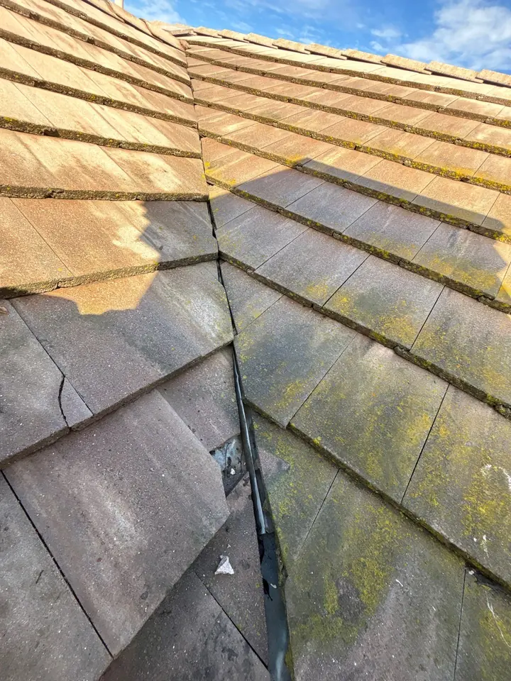 Concrete roof tiles cut tightly against valley metal with debris and restricted drainage
