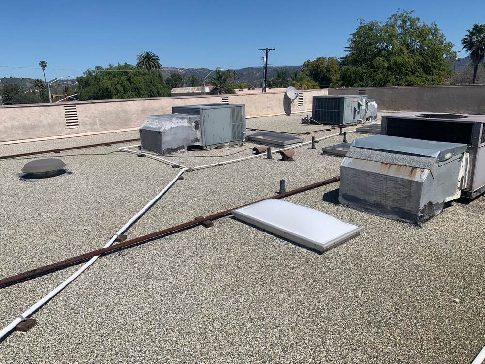 Commercial tar-and-gravel roof with HVAC equipment, skylights and rooftop pipes