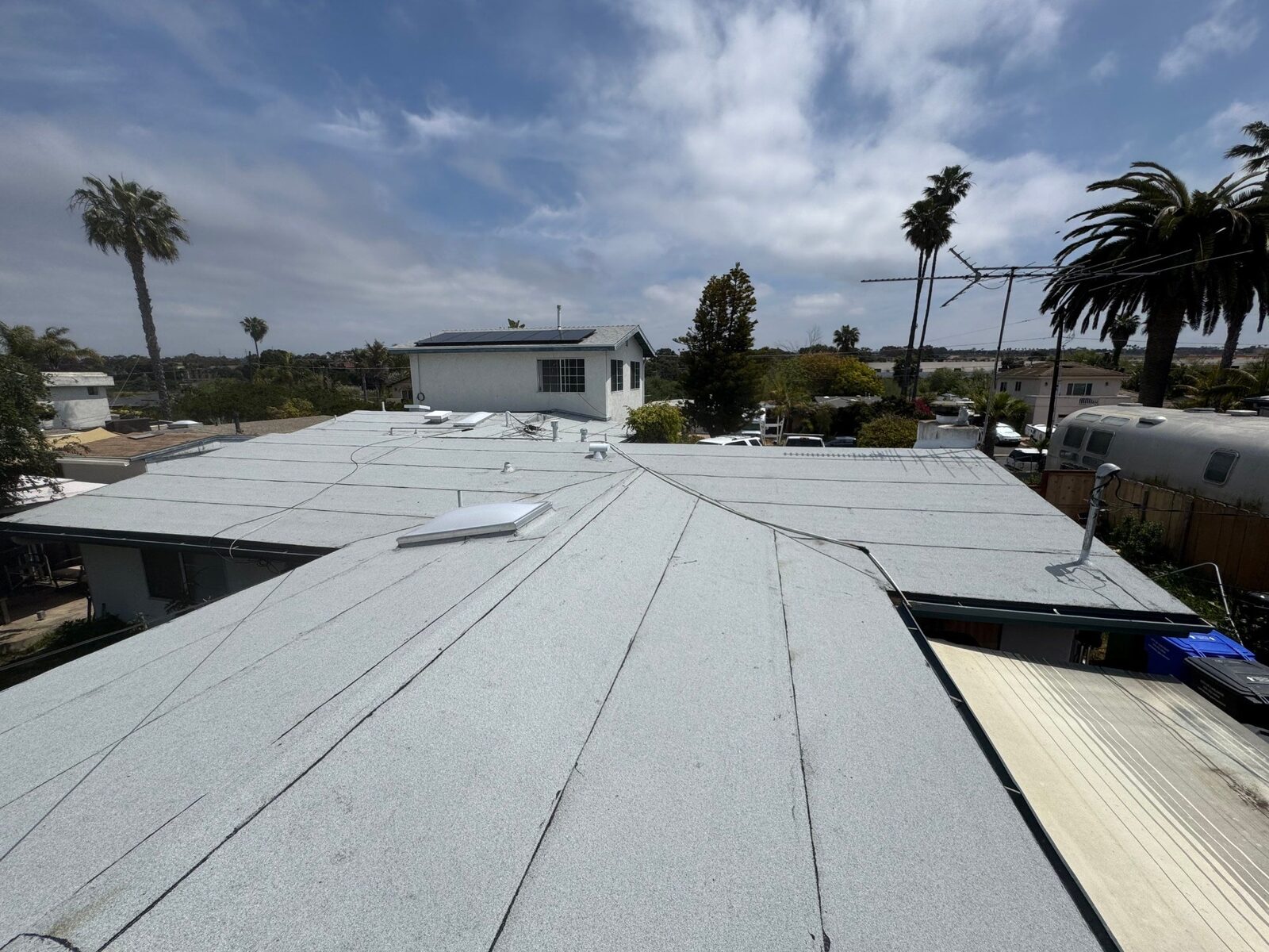 Existing modified-bitumen low-slope roof with skylights and solar panels