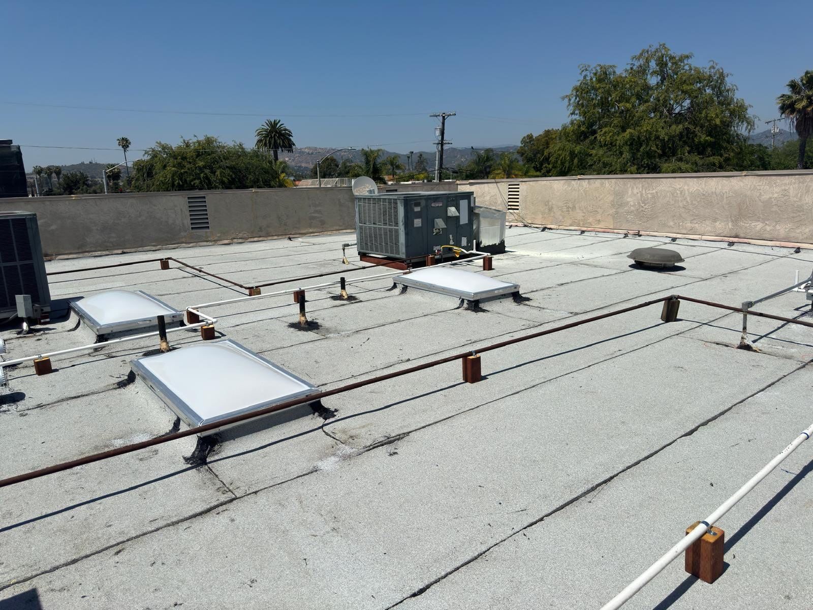 Completed white modified-bitumen roof around rooftop HVAC equipment and skylights