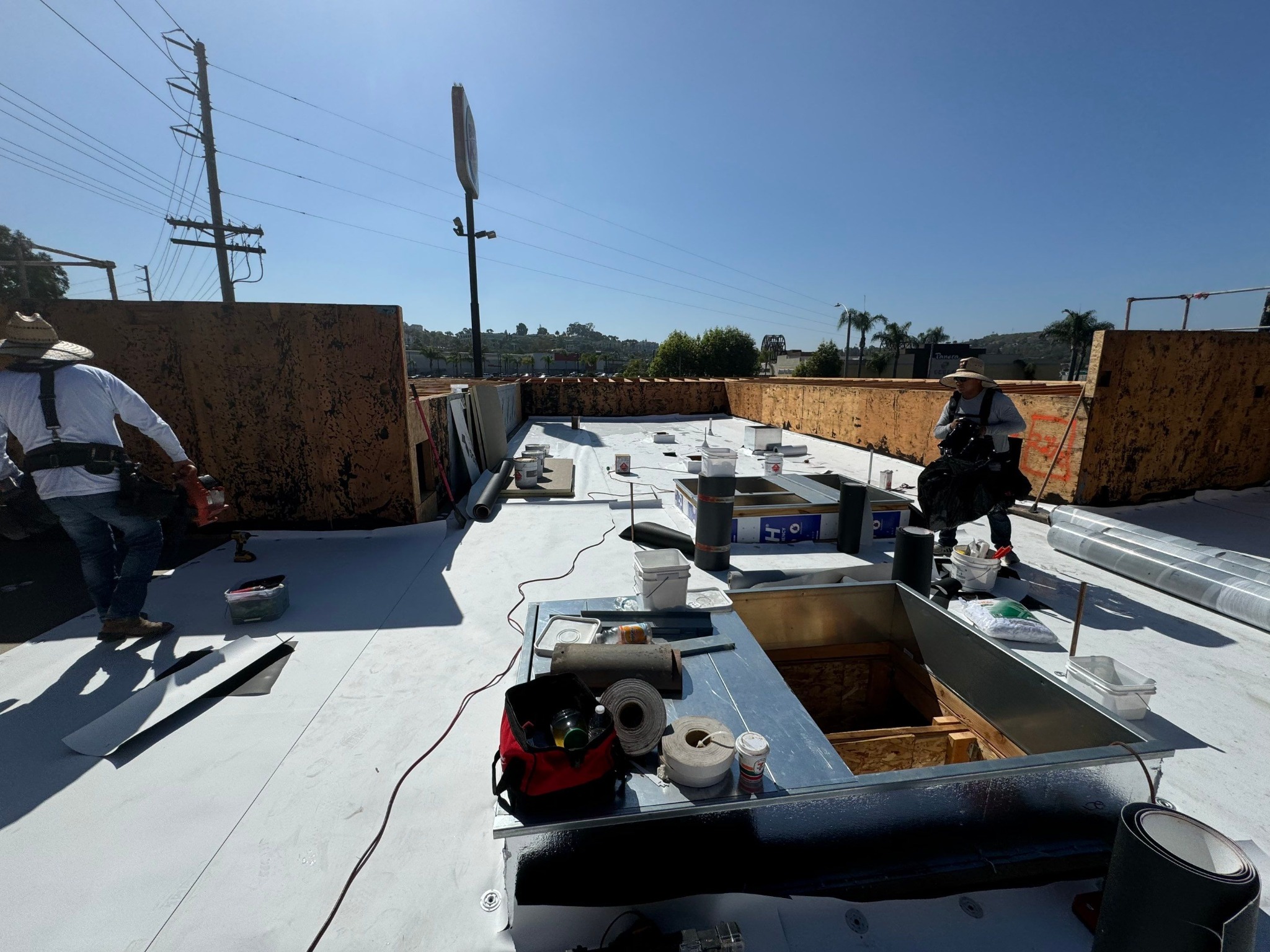 White TPO membrane being installed around commercial roof curbs